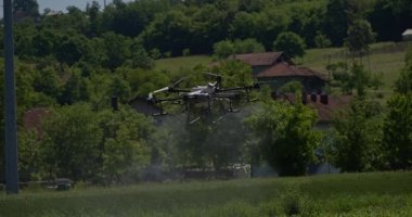 Kırsal ortamlardaki gelişmiş tarım teknolojisi ve hassas tarım tekniklerini vurgulayarak, ekin izleme veya spreyleme görevi sırasında ekili bir tarla üzerinde uçan hava aracı..