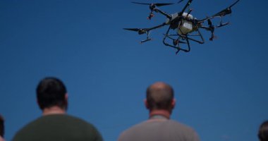 Yenilikçi bir çiftçi, günbatımında bir tarlanın ortasında dikilirken, tarım arazilerini modern akıllı tarım uygulamalarının bir parçası olarak incelemek ve tarlaları izlemek için hava teknolojisini kullanır..