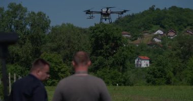 Yenilikçi bir çiftçi, günbatımında bir tarlanın ortasında dikilirken, tarım arazilerini modern akıllı tarım uygulamalarının bir parçası olarak incelemek ve tarlaları izlemek için hava teknolojisini kullanır..