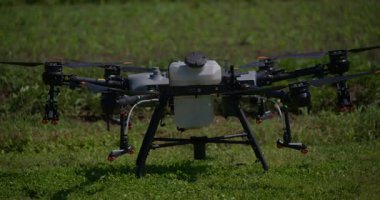 Kırsal ortamlardaki gelişmiş tarım teknolojisi ve hassas tarım tekniklerini vurgulayarak, ekin izleme veya spreyleme görevi sırasında ekili bir tarla üzerinde uçan hava aracı..