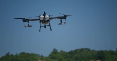 Kırsal ortamlardaki gelişmiş tarım teknolojisi ve hassas tarım tekniklerini vurgulayarak, ekin izleme veya spreyleme görevi sırasında ekili bir tarla üzerinde uçan hava aracı..