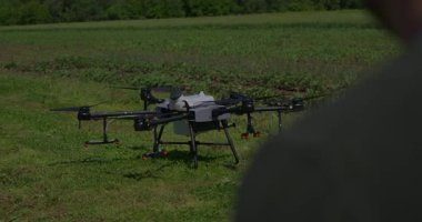 Yenilikçi bir çiftçi, günbatımında bir tarlanın ortasında dikilirken, tarım arazilerini modern akıllı tarım uygulamalarının bir parçası olarak incelemek ve tarlaları izlemek için hava teknolojisini kullanır..