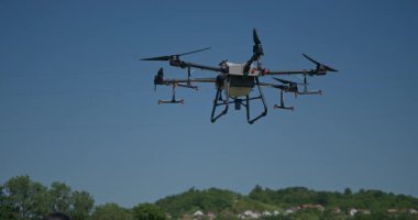 Kırsal ortamlardaki gelişmiş tarım teknolojisi ve hassas tarım tekniklerini vurgulayarak, ekin izleme veya spreyleme görevi sırasında ekili bir tarla üzerinde uçan hava aracı..