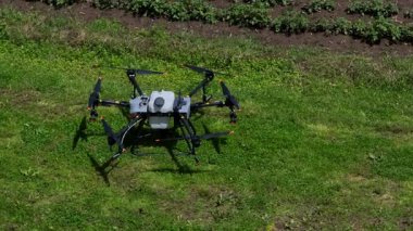 Kırsal ortamlardaki gelişmiş tarım teknolojisi ve hassas tarım tekniklerini vurgulayarak, ekin izleme veya spreyleme görevi sırasında ekili bir tarla üzerinde uçan hava aracı..