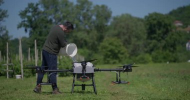 Modern yenilikçi çiftçi büyük bir tarım aracını yeşil alanda sıvı gübrelerle dolduruyor, modern akıllı çiftçilik, dron teknolojisi ve hassas tarım sergiliyor.