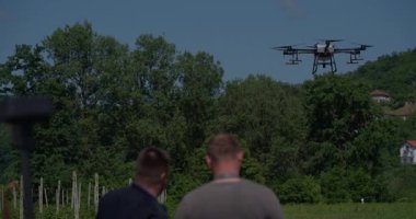 Yenilikçi bir çiftçi, günbatımında bir tarlanın ortasında dikilirken, tarım arazilerini modern akıllı tarım uygulamalarının bir parçası olarak incelemek ve tarlaları izlemek için hava teknolojisini kullanır..