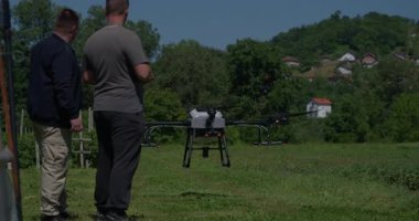 Yenilikçi bir çiftçi, günbatımında bir tarlanın ortasında dikilirken, tarım arazilerini modern akıllı tarım uygulamalarının bir parçası olarak incelemek ve tarlaları izlemek için hava teknolojisini kullanır..