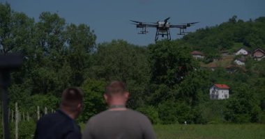 Yenilikçi bir çiftçi, günbatımında bir tarlanın ortasında dikilirken, tarım arazilerini modern akıllı tarım uygulamalarının bir parçası olarak incelemek ve tarlaları izlemek için hava teknolojisini kullanır..