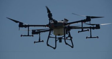 Kırsal ortamlardaki gelişmiş tarım teknolojisi ve hassas tarım tekniklerini vurgulayarak, ekin izleme veya spreyleme görevi sırasında ekili bir tarla üzerinde uçan hava aracı..