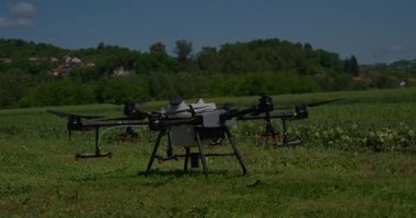 Kırsal ortamlardaki gelişmiş tarım teknolojisi ve hassas tarım tekniklerini vurgulayarak, ekin izleme veya spreyleme görevi sırasında ekili bir tarla üzerinde uçan hava aracı..