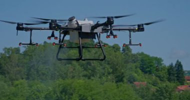 Kırsal ortamlardaki gelişmiş tarım teknolojisi ve hassas tarım tekniklerini vurgulayarak, ekin izleme veya spreyleme görevi sırasında ekili bir tarla üzerinde uçan hava aracı..