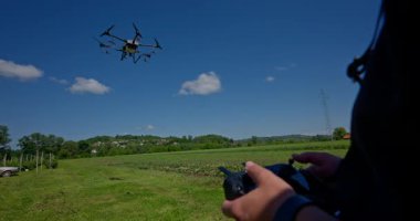 Yenilikçi bir çiftçi, günbatımında bir tarlanın ortasında dikilirken, tarım arazilerini modern akıllı tarım uygulamalarının bir parçası olarak incelemek ve tarlaları izlemek için hava teknolojisini kullanır..