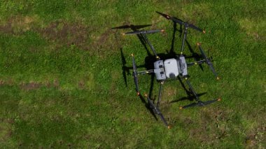 Kırsal ortamlardaki gelişmiş tarım teknolojisi ve hassas tarım tekniklerini vurgulayarak, ekin izleme veya spreyleme görevi sırasında ekili bir tarla üzerinde uçan hava aracı..