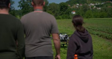 Yenilikçi bir çiftçi, günbatımında bir tarlanın ortasında dikilirken, tarım arazilerini modern akıllı tarım uygulamalarının bir parçası olarak incelemek ve tarlaları izlemek için hava teknolojisini kullanır..