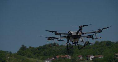 Kırsal ortamlardaki gelişmiş tarım teknolojisi ve hassas tarım tekniklerini vurgulayarak, ekin izleme veya spreyleme görevi sırasında ekili bir tarla üzerinde uçan hava aracı..