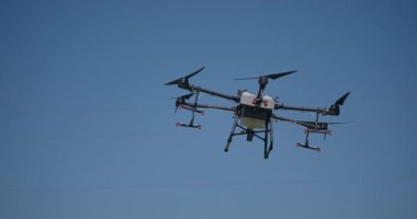 Kırsal ortamlardaki gelişmiş tarım teknolojisi ve hassas tarım tekniklerini vurgulayarak, ekin izleme veya spreyleme görevi sırasında ekili bir tarla üzerinde uçan hava aracı..