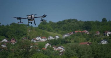 Kırsal ortamlardaki gelişmiş tarım teknolojisi ve hassas tarım tekniklerini vurgulayarak, ekin izleme veya spreyleme görevi sırasında ekili bir tarla üzerinde uçan hava aracı..