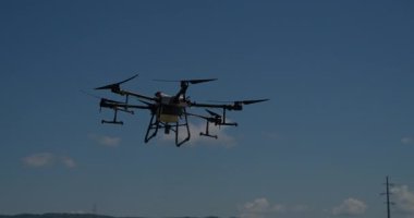 Kırsal ortamlardaki gelişmiş tarım teknolojisi ve hassas tarım tekniklerini vurgulayarak, ekin izleme veya spreyleme görevi sırasında ekili bir tarla üzerinde uçan hava aracı..