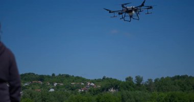 Kırsal ortamlardaki gelişmiş tarım teknolojisi ve hassas tarım tekniklerini vurgulayarak, ekin izleme veya spreyleme görevi sırasında ekili bir tarla üzerinde uçan hava aracı..