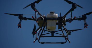 Kırsal ortamlardaki gelişmiş tarım teknolojisi ve hassas tarım tekniklerini vurgulayarak, ekin izleme veya spreyleme görevi sırasında ekili bir tarla üzerinde uçan hava aracı..