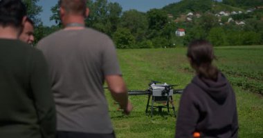 Yenilikçi bir çiftçi, günbatımında bir tarlanın ortasında dikilirken, tarım arazilerini modern akıllı tarım uygulamalarının bir parçası olarak incelemek ve tarlaları izlemek için hava teknolojisini kullanır..