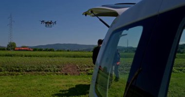 Yenilikçi bir çiftçi, günbatımında bir tarlanın ortasında dikilirken, tarım arazilerini modern akıllı tarım uygulamalarının bir parçası olarak incelemek ve tarlaları izlemek için hava teknolojisini kullanır..