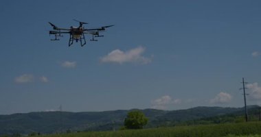 Kırsal ortamlardaki gelişmiş tarım teknolojisi ve hassas tarım tekniklerini vurgulayarak, ekin izleme veya spreyleme görevi sırasında ekili bir tarla üzerinde uçan hava aracı..