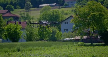 Kırsal ortamlardaki gelişmiş tarım teknolojisi ve hassas tarım tekniklerini vurgulayarak, ekin izleme veya spreyleme görevi sırasında ekili bir tarla üzerinde uçan hava aracı..