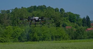 Kırsal ortamlardaki gelişmiş tarım teknolojisi ve hassas tarım tekniklerini vurgulayarak, ekin izleme veya spreyleme görevi sırasında ekili bir tarla üzerinde uçan hava aracı..