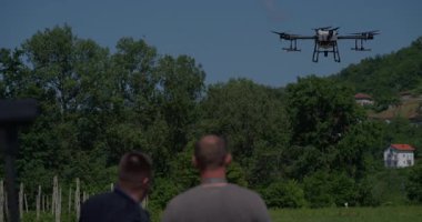 Yenilikçi bir çiftçi, günbatımında bir tarlanın ortasında dikilirken, tarım arazilerini modern akıllı tarım uygulamalarının bir parçası olarak incelemek ve tarlaları izlemek için hava teknolojisini kullanır..