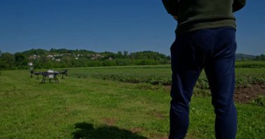 Yenilikçi bir çiftçi, günbatımında bir tarlanın ortasında dikilirken, tarım arazilerini modern akıllı tarım uygulamalarının bir parçası olarak incelemek ve tarlaları izlemek için hava teknolojisini kullanır..