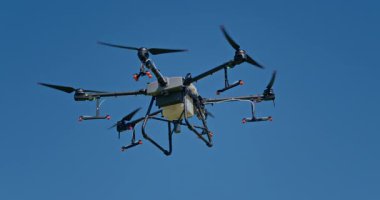 Kırsal ortamlardaki gelişmiş tarım teknolojisi ve hassas tarım tekniklerini vurgulayarak, ekin izleme veya spreyleme görevi sırasında ekili bir tarla üzerinde uçan hava aracı..