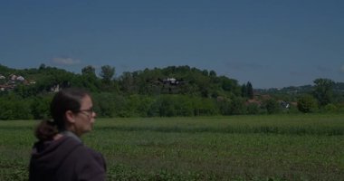 Yenilikçi bir dişi çiftçi, günbatımında bir tarlanın ortasında dikilirken, tarım arazilerini modern akıllı tarım uygulamalarının bir parçası olarak incelemek ve izlemek için hava teknolojisini kullanır..
