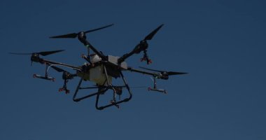 Kırsal ortamlardaki gelişmiş tarım teknolojisi ve hassas tarım tekniklerini vurgulayarak, ekin izleme veya spreyleme görevi sırasında ekili bir tarla üzerinde uçan hava aracı..