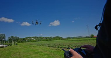 Yenilikçi bir çiftçi, günbatımında bir tarlanın ortasında dikilirken, tarım arazilerini modern akıllı tarım uygulamalarının bir parçası olarak incelemek ve tarlaları izlemek için hava teknolojisini kullanır..