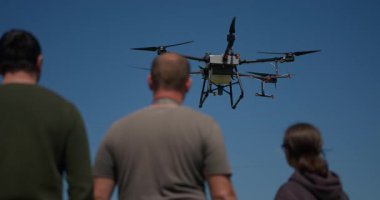 Yenilikçi bir çiftçi, günbatımında bir tarlanın ortasında dikilirken, tarım arazilerini modern akıllı tarım uygulamalarının bir parçası olarak incelemek ve tarlaları izlemek için hava teknolojisini kullanır..