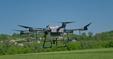 Kırsal ortamlardaki gelişmiş tarım teknolojisi ve hassas tarım tekniklerini vurgulayarak, ekin izleme veya spreyleme görevi sırasında ekili bir tarla üzerinde uçan hava aracı..