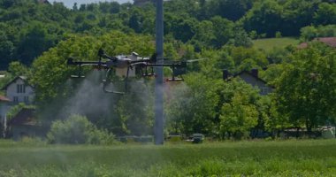 Kırsal ortamlardaki gelişmiş tarım teknolojisi ve hassas tarım tekniklerini vurgulayarak, ekin izleme veya spreyleme görevi sırasında ekili bir tarla üzerinde uçan hava aracı..