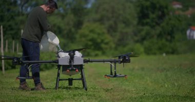 Modern yenilikçi çiftçi büyük bir tarım aracını yeşil alanda sıvı gübrelerle dolduruyor, modern akıllı çiftçilik, dron teknolojisi ve hassas tarım sergiliyor.