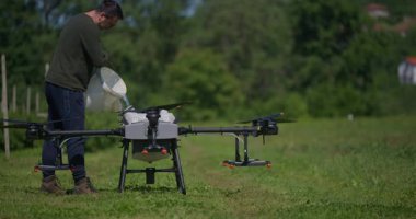Modern yenilikçi çiftçi büyük bir tarım aracını yeşil alanda sıvı gübrelerle dolduruyor, modern akıllı çiftçilik, dron teknolojisi ve hassas tarım sergiliyor.