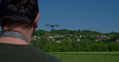 Yenilikçi bir çiftçi, günbatımında bir tarlanın ortasında dikilirken, tarım arazilerini modern akıllı tarım uygulamalarının bir parçası olarak incelemek ve tarlaları izlemek için hava teknolojisini kullanır..