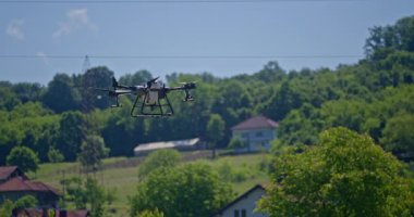 Kırsal ortamlardaki gelişmiş tarım teknolojisi ve hassas tarım tekniklerini vurgulayarak, ekin izleme veya spreyleme görevi sırasında ekili bir tarla üzerinde uçan hava aracı..