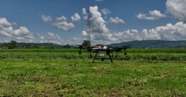 Kırsal ortamlardaki gelişmiş tarım teknolojisi ve hassas tarım tekniklerini vurgulayarak, ekin izleme veya spreyleme görevi sırasında ekili bir tarla üzerinde uçan hava aracı..