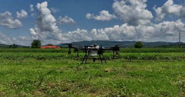 Kırsal ortamlardaki gelişmiş tarım teknolojisi ve hassas tarım tekniklerini vurgulayarak, ekin izleme veya spreyleme görevi sırasında ekili bir tarla üzerinde uçan hava aracı..