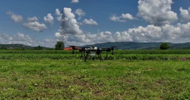 Kırsal ortamlardaki gelişmiş tarım teknolojisi ve hassas tarım tekniklerini vurgulayarak, ekin izleme veya spreyleme görevi sırasında ekili bir tarla üzerinde uçan hava aracı..