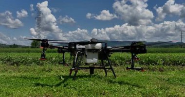 Kırsal ortamlardaki gelişmiş tarım teknolojisi ve hassas tarım tekniklerini vurgulayarak, ekin izleme veya spreyleme görevi sırasında ekili bir tarla üzerinde uçan hava aracı..