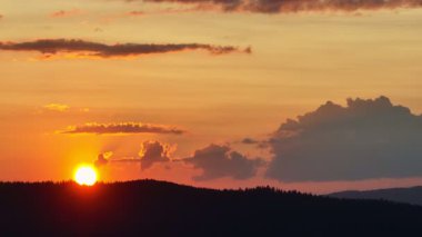Gün batımında parlayan güneş, sıcak turuncu gökyüzü ve uzun çam ağaçları olan manzaralı orman silueti. Huzurlu, sakin doğa manzarası sakinlik, sükunet ve güzellik temaları için mükemmeldir.