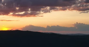 Gün batımında parlayan güneş, sıcak turuncu gökyüzü ve uzun çam ağaçları olan manzaralı orman silueti. Huzurlu, sakin doğa manzarası sakinlik, sükunet ve güzellik temaları için mükemmeldir.