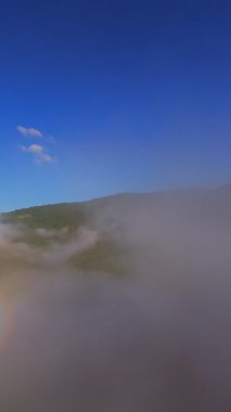 Güneşin doğuşuyla birlikte yemyeşil bir vadinin hava dikey videosu sisli tepeler, orman ağaçları ve yumuşak sabah ışığı. Seyahat, ekolojik maceralar ve manzaralı kaçışlar için mükemmel güzel, sinematik bir manzara.