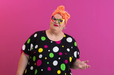 Artı puantiyeli kadın pembe arka planda karışık bir ifadeyle omuz silkiyor.. 